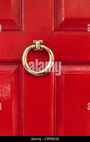 Bague en laiton poli brillant sur heurtoir de porte peint brillant rouge, London, England, UK Banque D'Images