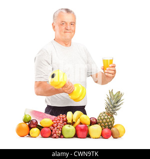 Mature man holding un haltère et verre de jus avec des tas de fruits et légumes frais isolated on white Banque D'Images