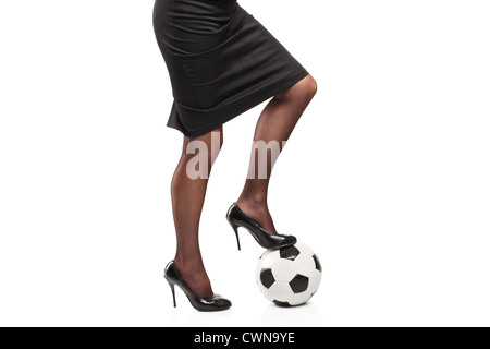 Femme en hauts talons debout sur un ballon de soccer isolé sur fond blanc Banque D'Images