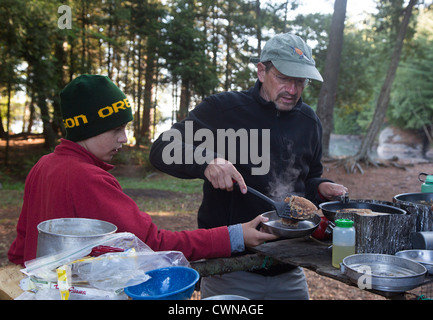 Le Parc Provincial Algonquin, Ontario Canada - John West, 65 cuisiniers, des crêpes pour son fils Joey, 13, au cours d'une excursion en canot. Banque D'Images