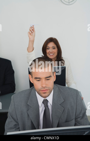 Businesswoman throwing paper airplane au collègue masculin Banque D'Images