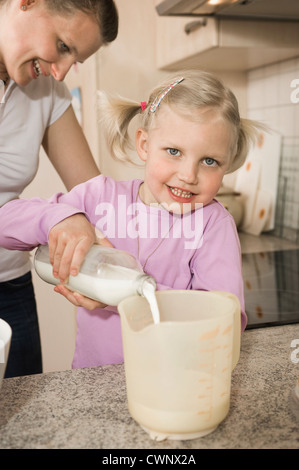 Mère et fille de verser le lait en verre mesureur Banque D'Images