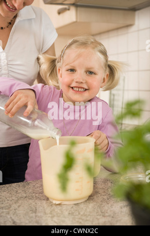 Mère et fille de verser le lait en verre mesureur Banque D'Images