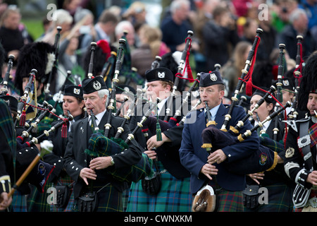 Les corps de pipe band parade autour du terrain de sport à la collecte pendant la Braemar Highland Games. Banque D'Images