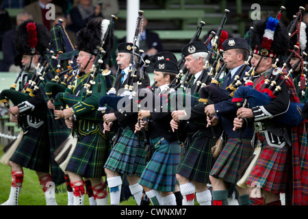 Les corps de pipe band parade autour du terrain de sport à la collecte pendant la Braemar Highland Games. Banque D'Images