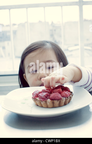 Petite fille collant doigts dans la tarte aux fruits Banque D'Images