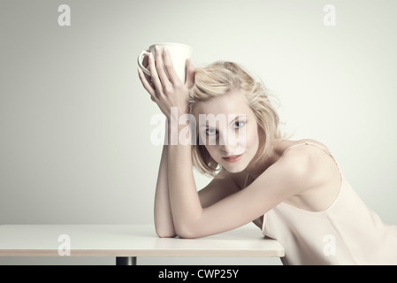 Young woman holding Coffee cup à table, portrait Banque D'Images