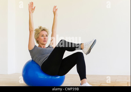 Femme mature faire pilates exercice sur fitness ball Banque D'Images