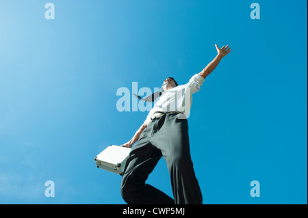 Businessman jumping dans l'air carrying briefcase, low angle view Banque D'Images