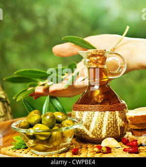 L''huile d''olive, woman's hand holding feuilles d'olive branch, vert fruits frais dans des bols en verre transparent, d'une saine alimentation Banque D'Images