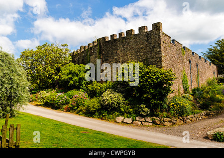 Arbres et arbustes forment un joli cadre autour de grands murs en pierre crénelées entourant le restaurant du Château de Muncaster Banque D'Images