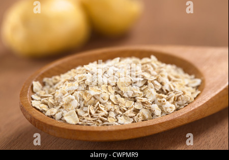 Gruau mélangé avec de la poudre de maca ou ginseng péruvien (lat. Le Lepidium meyenii) sur cuillère en bois avec des racines de maca dans le dos Banque D'Images