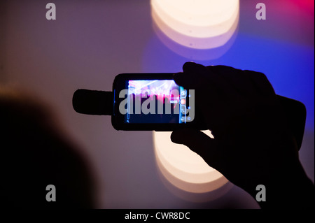 Une personne titulaire d'un téléphone mobile de filmer filmer l'enregistrement d'un groupe jouant de la musique au concert concert manifestation UK Banque D'Images