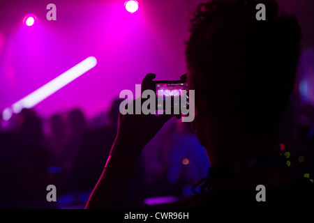 Une personne avec un téléphone mobile de l'enregistrement d'un groupe jouant de la musique au concert concert manifestation UK Banque D'Images