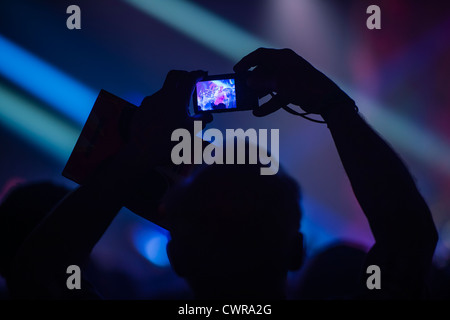 Une personne titulaire d'un téléphone mobile l'enregistrement d'un groupe jouant de la musique au concert concert manifestation UK Banque D'Images