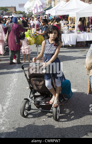 Jeune fille attend que maman avec petit frère dans la poussette sur l'avenue McDonald (Little Bangladesh) Brooklyn, New York. Banque D'Images