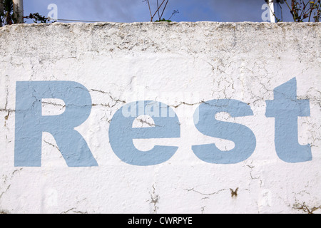 'Lettrage reste', style pochoir peinture bleu ciel sur un mur blanc, l'effritement et distressed look, Cornwall, UK Banque D'Images