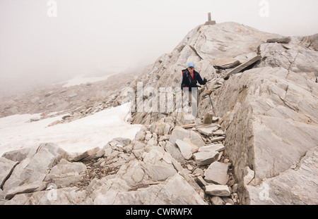 Un randonneur s'approche d'un marqueur au sommet du Monte Moro Passer à la frontière de la Suisse et l'Italie dans les Alpes. Banque D'Images