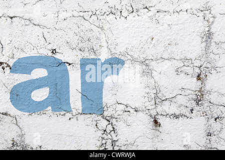 'Ar' lettrage, style pochoir peinture bleu ciel sur un mur blanc, l'effritement et distressed look, Cornwall, UK Banque D'Images