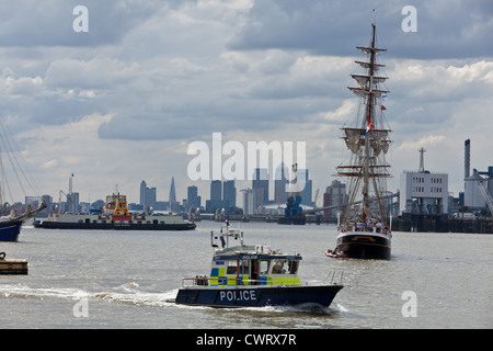 Grand voilier bateau de la police et de Woolwich ferry dans l'avant-plan sur la Tamise avec une vue sur les toits de Londres Banque D'Images