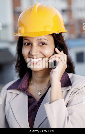 Happy Indian female construction engineer talking on cellphone Banque D'Images