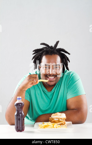 Fat african american man eating chips Banque D'Images