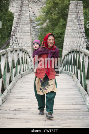 Balti villageoise avec un petit enfant, en traversant une passerelle dans la vallée de Nubra du Ladakh, Inde du nord. Banque D'Images