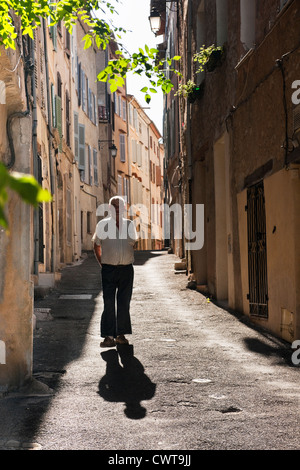 Un homme âgé marche sur une journée ensoleillée dans une rue de maisons hautes à Callas, Provence, France, Europe Banque D'Images