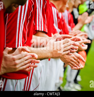 Trois joueurs de football sur terrain de soccer applaudir Banque D'Images