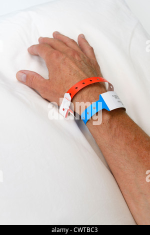 Mains et bras d'un homme à l'hôpital avec les bracelets d'identification Banque D'Images