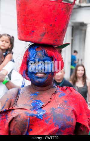 Les participants au congrès annuel de Notting Hill Carnival 2012 enduit de peinture rouge et bleu et portant un seau sur la tête. Banque D'Images