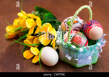 Oeufs de Pâques dans un panier de paille tissée avec des fleurs Banque D'Images