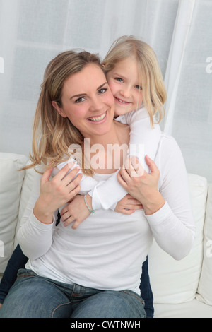 Mère et fille de câlins sur canapé Banque D'Images