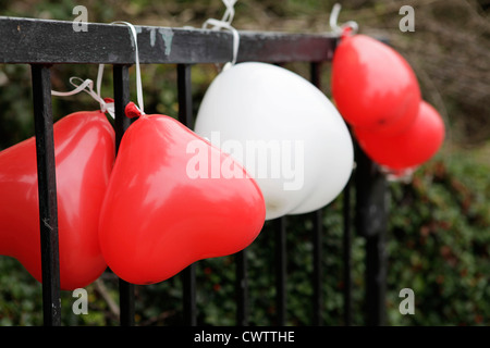 Ballons en forme de cœur à une clôture Banque D'Images