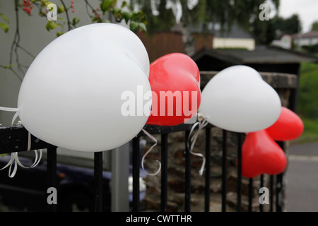 Ballons en forme de cœur à une clôture Banque D'Images