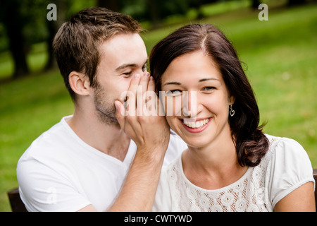 Jeune homme chuchoter à femme (COPINE) - photo de vie de plein air Banque D'Images