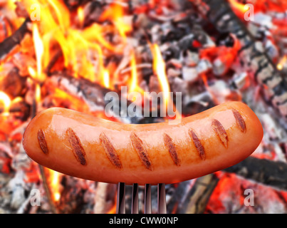 Saucisses sur une fourchette. Dans l'arrière-plan en feu. Banque D'Images