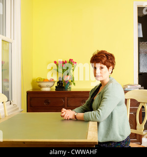 Femme assise à la table de cuisine Banque D'Images