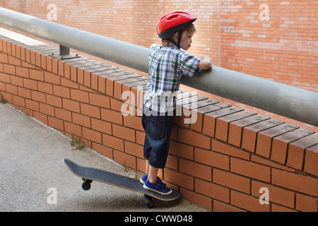 Boy peering over balcon extérieur Banque D'Images