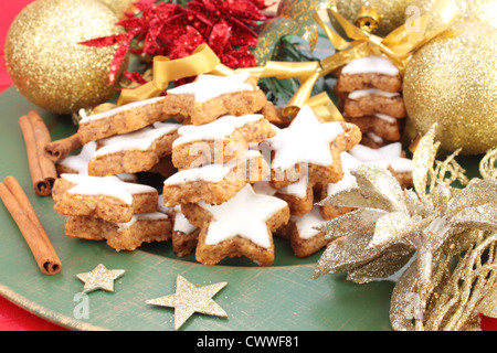 Star-shaped Christmas cookies à la cannelle sur une plaque verte. Décoré avec des décorations de Noël et des bâtons de cannelle. Banque D'Images