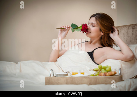 Woman relaxing with breakfast in bed Banque D'Images