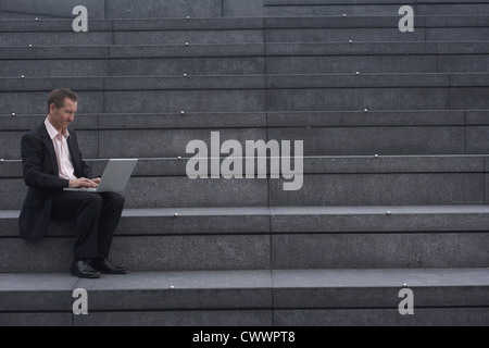 Businessman reading newspaper on steps Banque D'Images