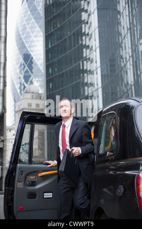 Businessman climbing out of taxi cab Banque D'Images