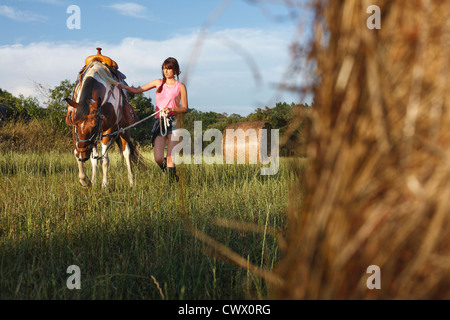 Woman walking horse in meadow Banque D'Images