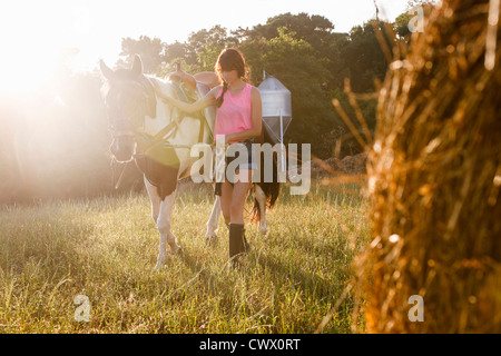 Woman walking horse in meadow Banque D'Images