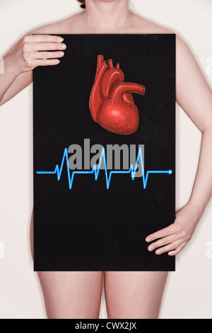 Femme tenant un tableau noir avec une illustration d'un coeur humain et d'un ECG pulse dessiné dessus à la craie. Image Concept Banque D'Images