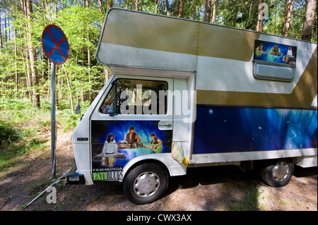 Un camping-car stationné dans une forêt à un arrêt sans signe de la circulation dans le nord de la Pologne. Banque D'Images