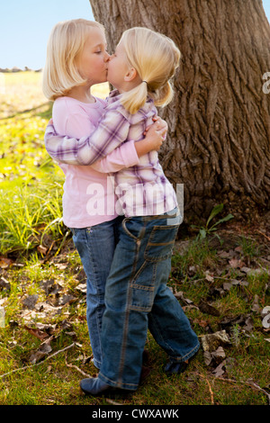 Les blondes lits jumeaux sont debout à côté de l'autre en face d'un arbre. Banque D'Images