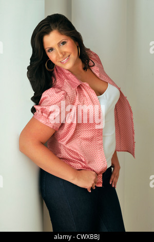 De taille plus attrayant model wearing red blouse debout contre un mur blanc en studio portrait. Banque D'Images