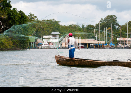 Le Garifuna pêcheur en pirogue voile casting filet de pêche sur le lac d'Izabal, Lago de Izabal, Guatemala. Banque D'Images